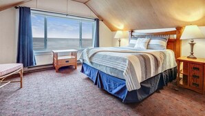Un dormitorio con una cama grande, una ventana con cortinas, una mesita de noche y una lámpara.