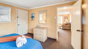 Une chambre d’hôtel comprenant un lit, une commode, un miroir et une porte donnant sur une autre pièce.