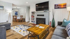 Ein Wohnzimmer mit Kamin, einer Essecke mit Tisch und Stühlen sowie einer Couch.