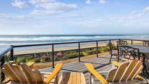 A wooden deck with chairs and a table overlooking the ocean. - Schilling Beach House (Arch Cape)