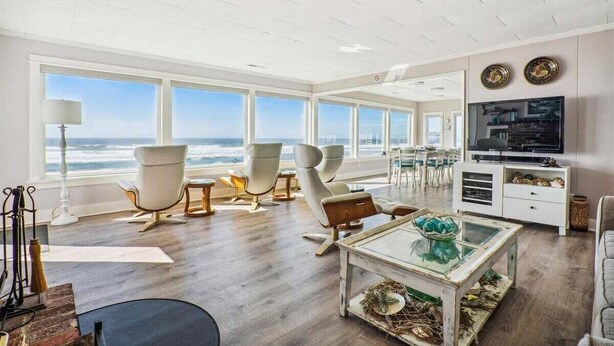 A spacious living room with large windows, a television, and modern furniture. - Schilling Beach House (Arch Cape)