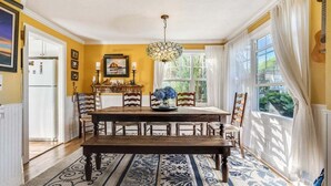 Comedor con mesa y sillas de madera, alfombra estampada y candelabro.