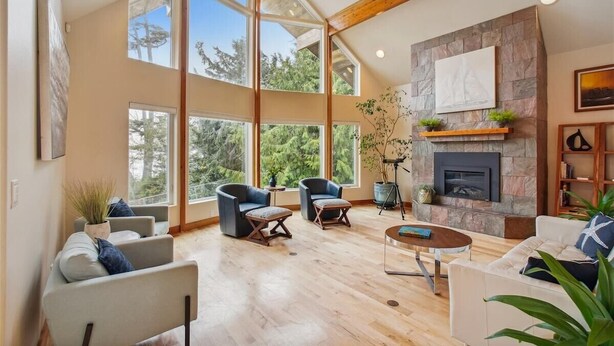 A spacious living room with large windows, a fireplace, and modern furniture. - Santo Cristo - Ocean View! (Arch Cape)