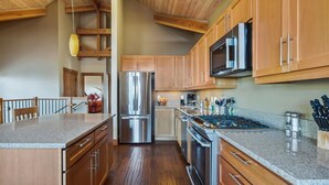 Une cuisine moderne avec des meubles en bois, des appareils en acier inoxydable et un plan de travail en granit.