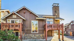 Un bâtiment à deux étages, doté d’une cheminée en pierre, de balcons en bois et de fondations en pierre.