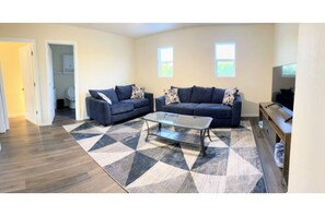 A living room with a sofa set, a coffee table, and a TV stand.