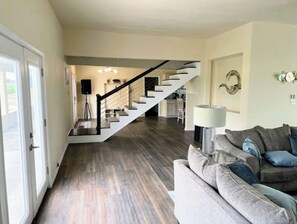 A living room with a staircase, a sofa, and a lamp.