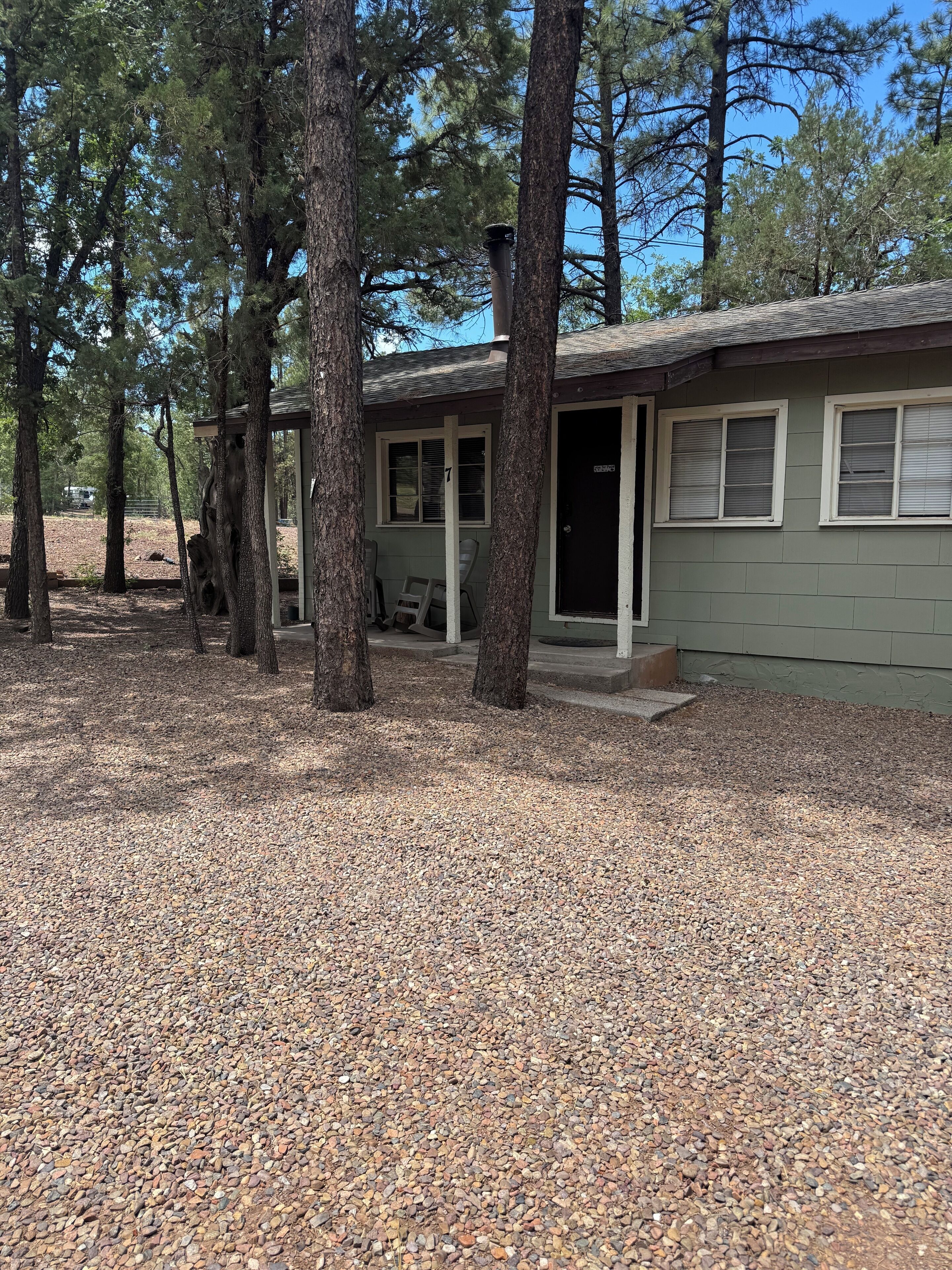 A single-story building with a gravel driveway and a covered outdoor seating area.
