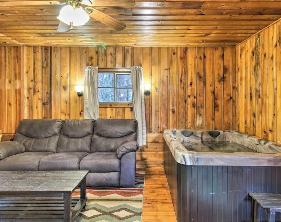 A wooden interior with a sofa, a hot tub, and a ceiling fan.