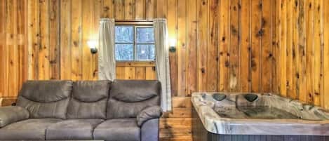 A wooden interior with a sofa, a hot tub, and a ceiling fan.