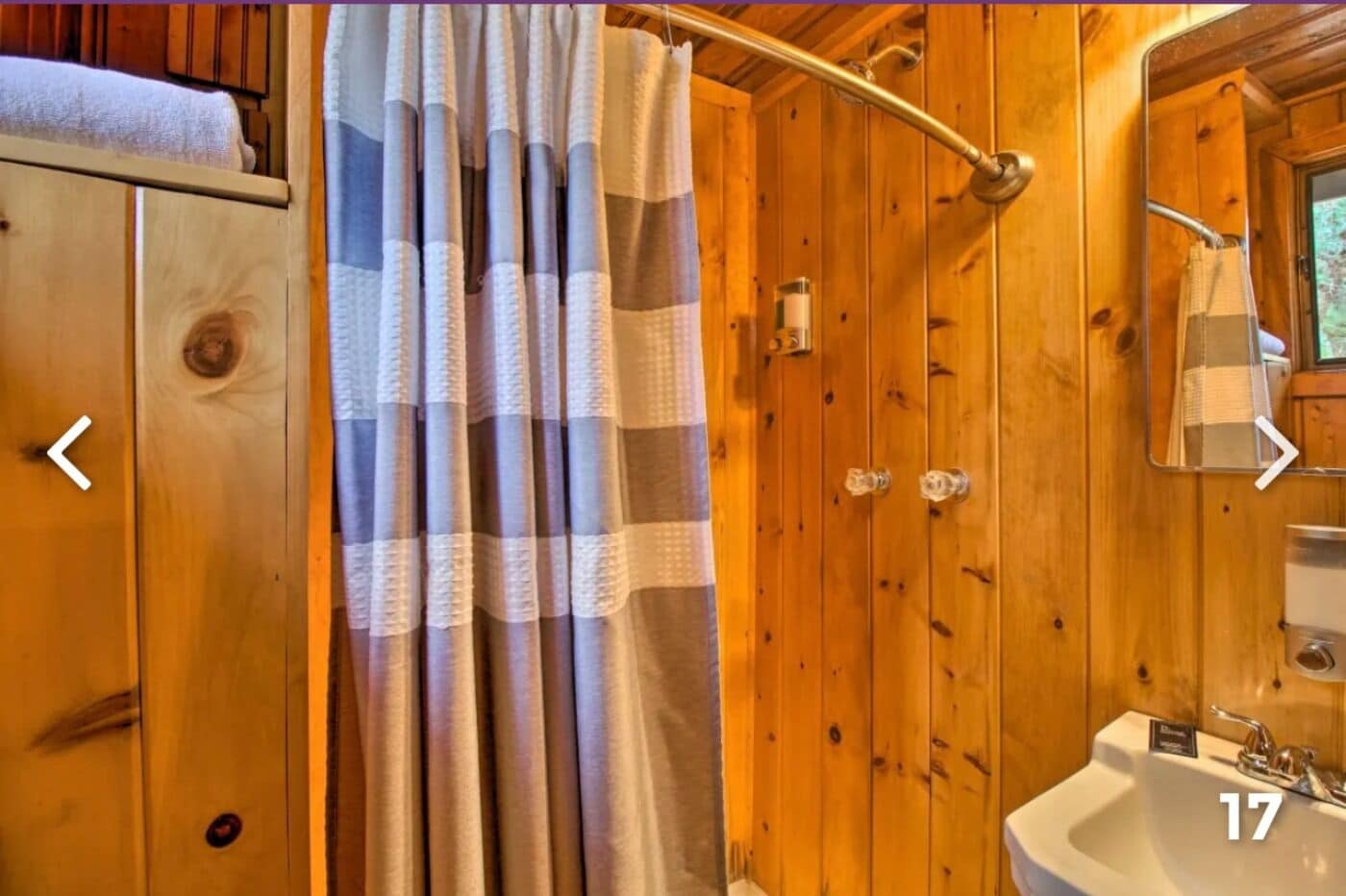 A wooden bathroom with a shower curtain, a sink, and a mirror.