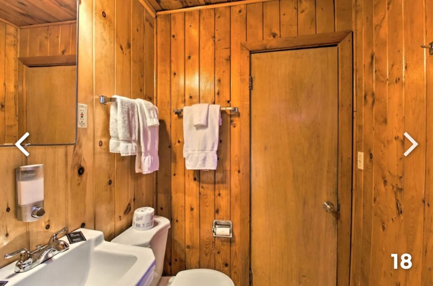 A wooden bathroom with a sink, toilet, and towel rack.