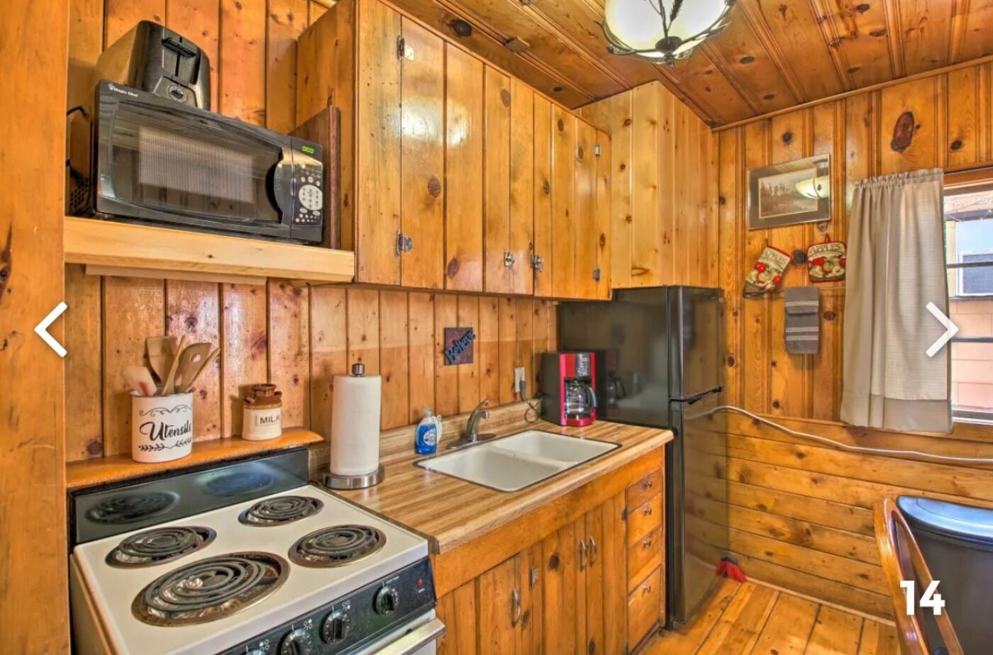 Eine Holzhütte mit einer Küche, inklusive Herd, Mikrowelle, Kühlschrank und Spüle.