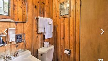 A wooden-paneled bathroom with a bathtub, toilet, and towel rack.