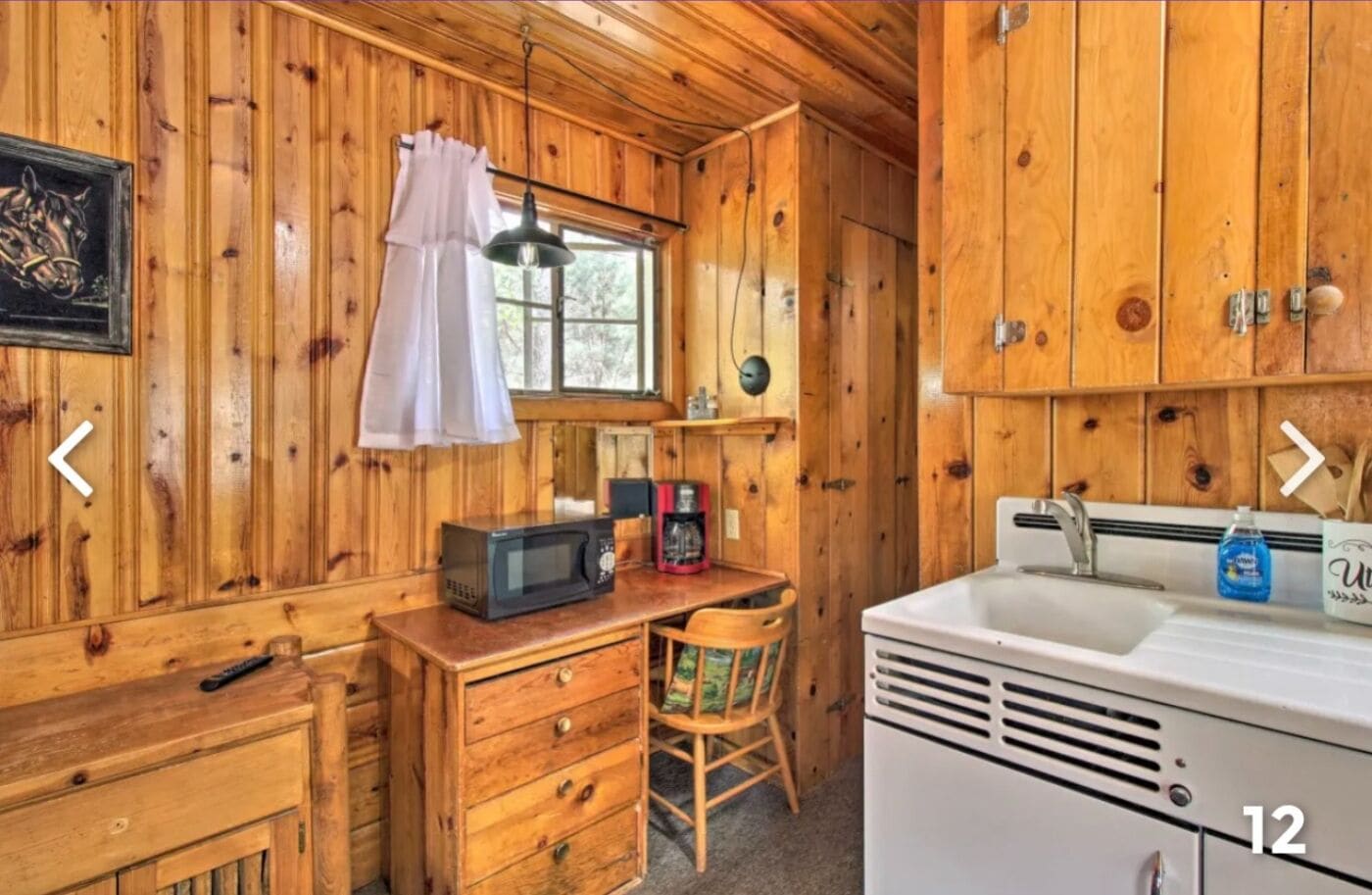 A compact kitchen with wooden walls, a microwave, a coffee maker, and a sink.