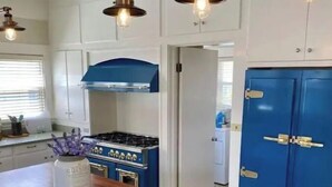 Een keuken met een houten tafel, een fornuis en blauwe kastjes.