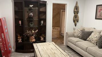Een woonkamer met een donker houten kast, een houten salontafel en een beige bank met gestreepte kussens.
