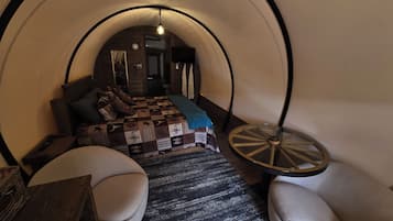 Une pièce circulaire et accueillante, avec un lit, une petite table et deux chaises.
