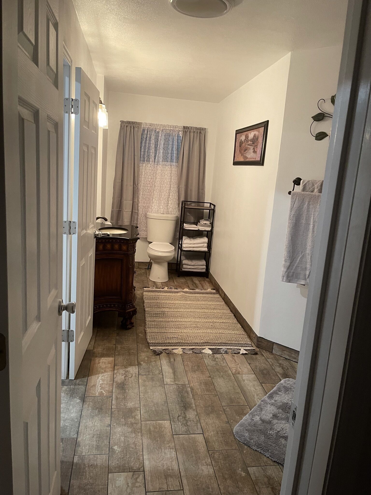A narrow bathroom with a toilet, a sink, and a shower area.