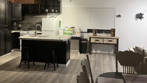 A modern kitchen with a central island, dark cabinetry, and a dining area with a wooden table and chairs. - Crazy Horse Rv Resort (Kanab)