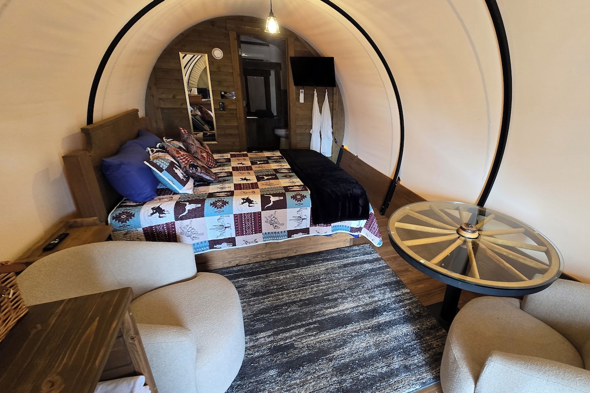 A cozy room with a bed, a round table, and a unique arched ceiling.