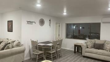 Una sala de estar con una mesa de comedor, dos sofás, un reloj y una ventana.
