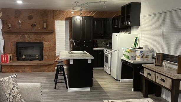 A modern kitchen with dark cabinets, a central island, and a built-in oven. - Crazy Horse Rv Resort (Kanab)