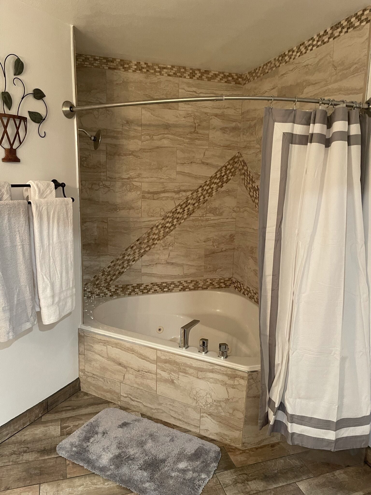 A corner bathroom with a freestanding bathtub, a shower curtain, and a towel rack with towels.