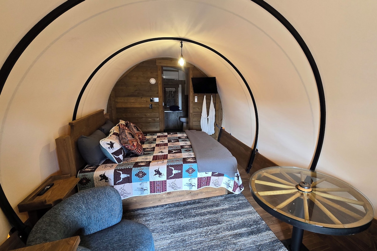 A cozy, circular room with a bed, a round table, and a bench.