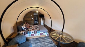 A cozy, circular room with a bed, a round table, and a bench.
