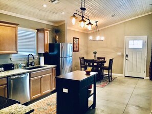 A kitchen with wooden cabinets, a stainless steel refrigerator, and a dining area with a table and chairs.