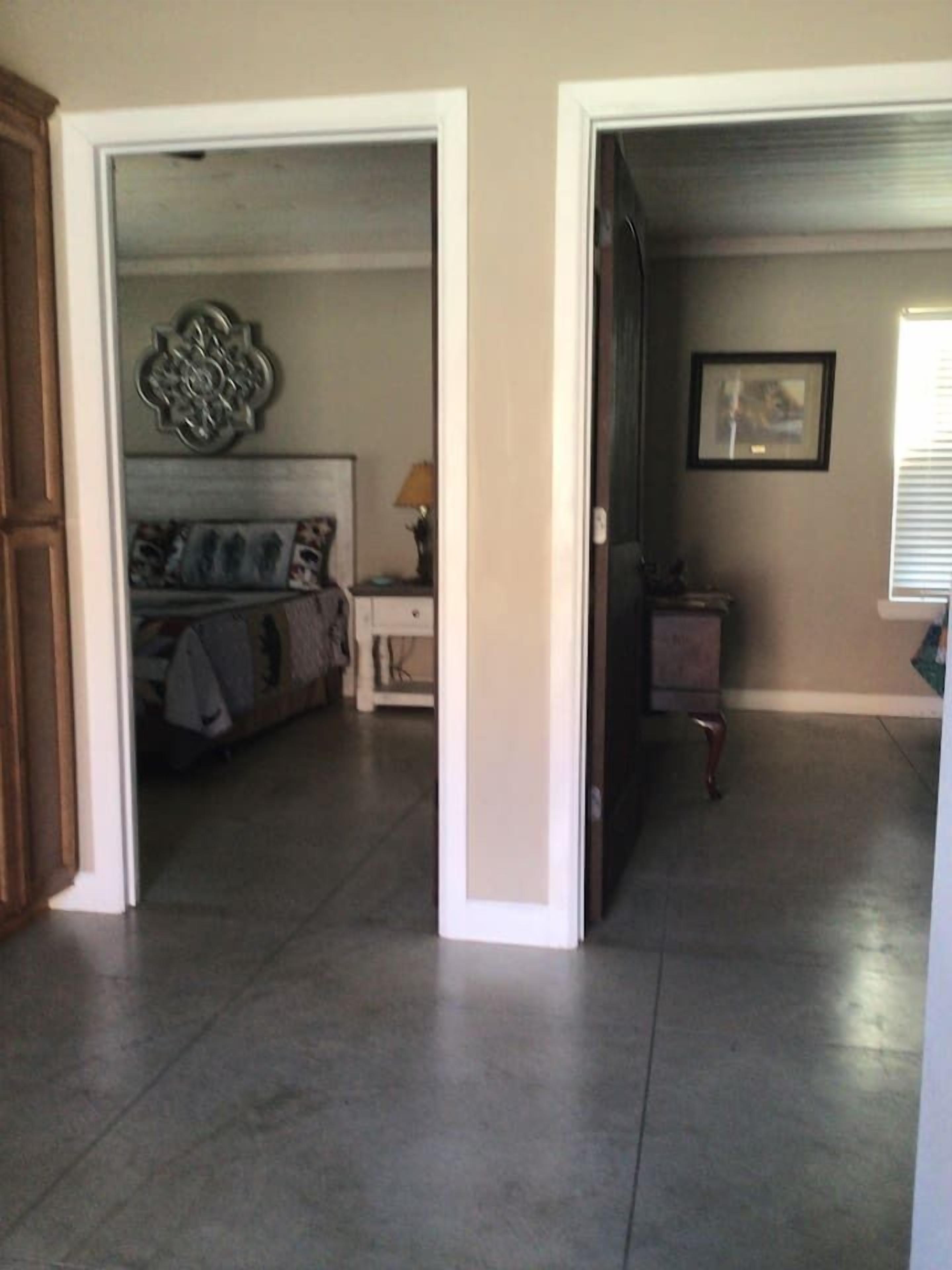 A hallway with a bed, bedside table, lamp, and a framed picture on the wall.