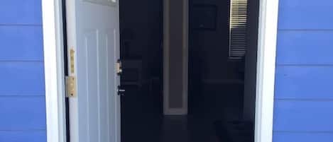 Un acceso que da a un espacio interior tenuemente iluminado, con un banco y un marco de puerta a la vista.