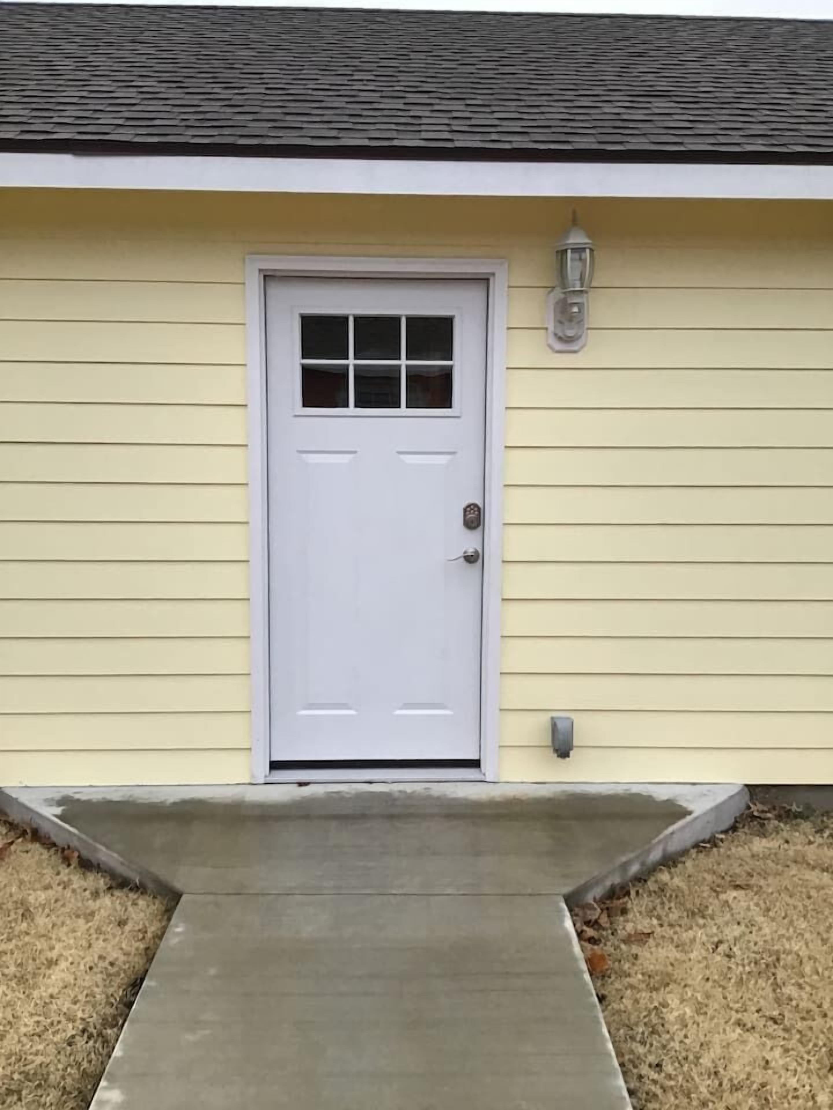 A single-story building with a white door, a small porch, and a light fixture above the door.