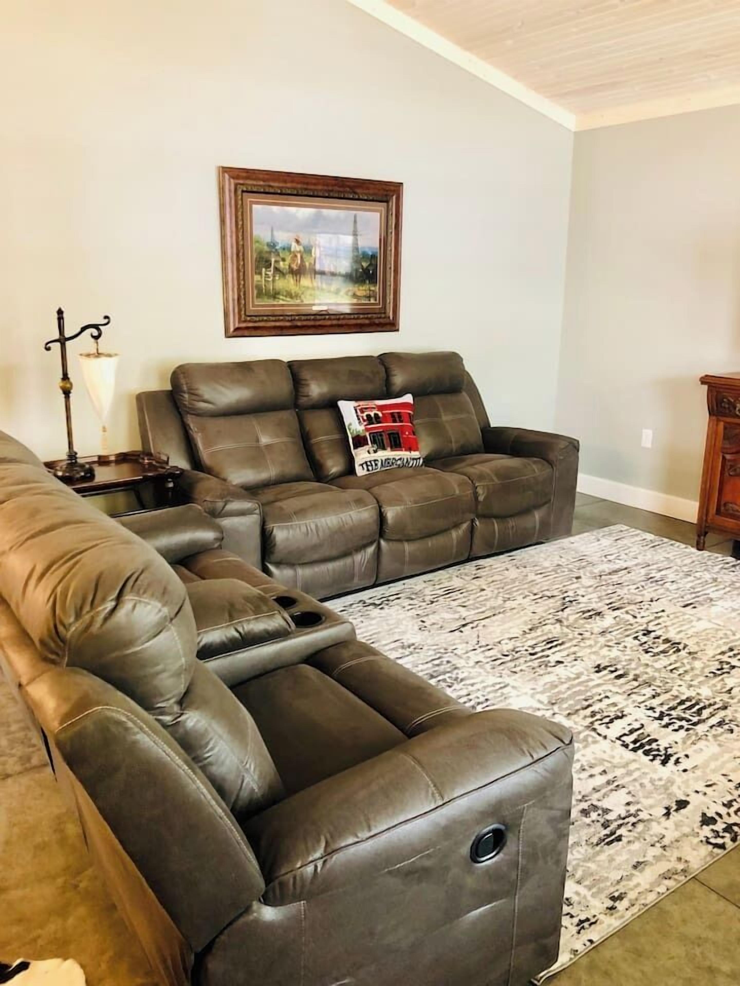 A living room with a sectional sofa, a rug, and a framed picture on the wall.