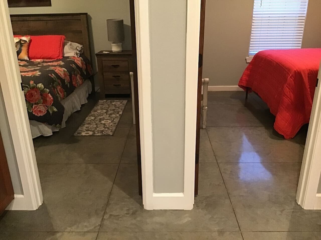 A bedroom with a bed, a nightstand, a lamp, and a window with blinds.
