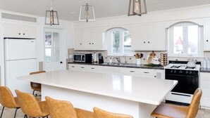 A modern kitchen with white cabinets, a large island, and pendant lighting. - Spacious & Quiet Amish Farm Stay - 16+ Guests (Leola)