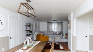 A modern living room with a wooden dining table, a sofa, and a cowhide rug. - Spacious & Quiet Amish Farm Stay - 16+ Guests (Leola)
