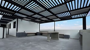 Ein geräumiges, modernes Büro mit hoher Decke und Oberlichtern, das einen zentralen Schreibtischbereich und integrierte Sitzgelegenheiten bietet.