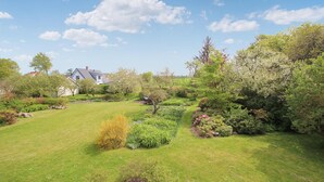 A well-maintained garden with a variety of plants and trees, a lawn, and a house in the background. - 3 bedroom gorgeous apartment in Samsø (Samsø)