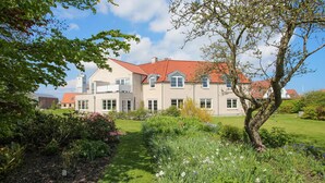 A two-story house with a red-tiled roof, surrounded by a well-maintained garden with various plants and flowers. - 3 bedroom gorgeous apartment in Samsø (Samsø)