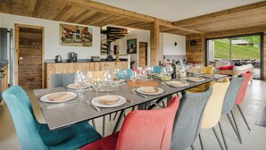 Un espace repas avec une longue table dressée pour le repas, entourée de chaises aux couleurs vives.