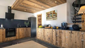 A modern kitchen with wooden cabinetry, a black refrigerator, and a coffee machine.
