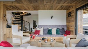 A cozy living room with a sofa, armchairs, a coffee table, and a fireplace.