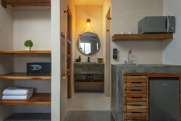 A bathroom with a wooden vanity, a sink, a mirror, a towel rack, and a microwave above the counter.