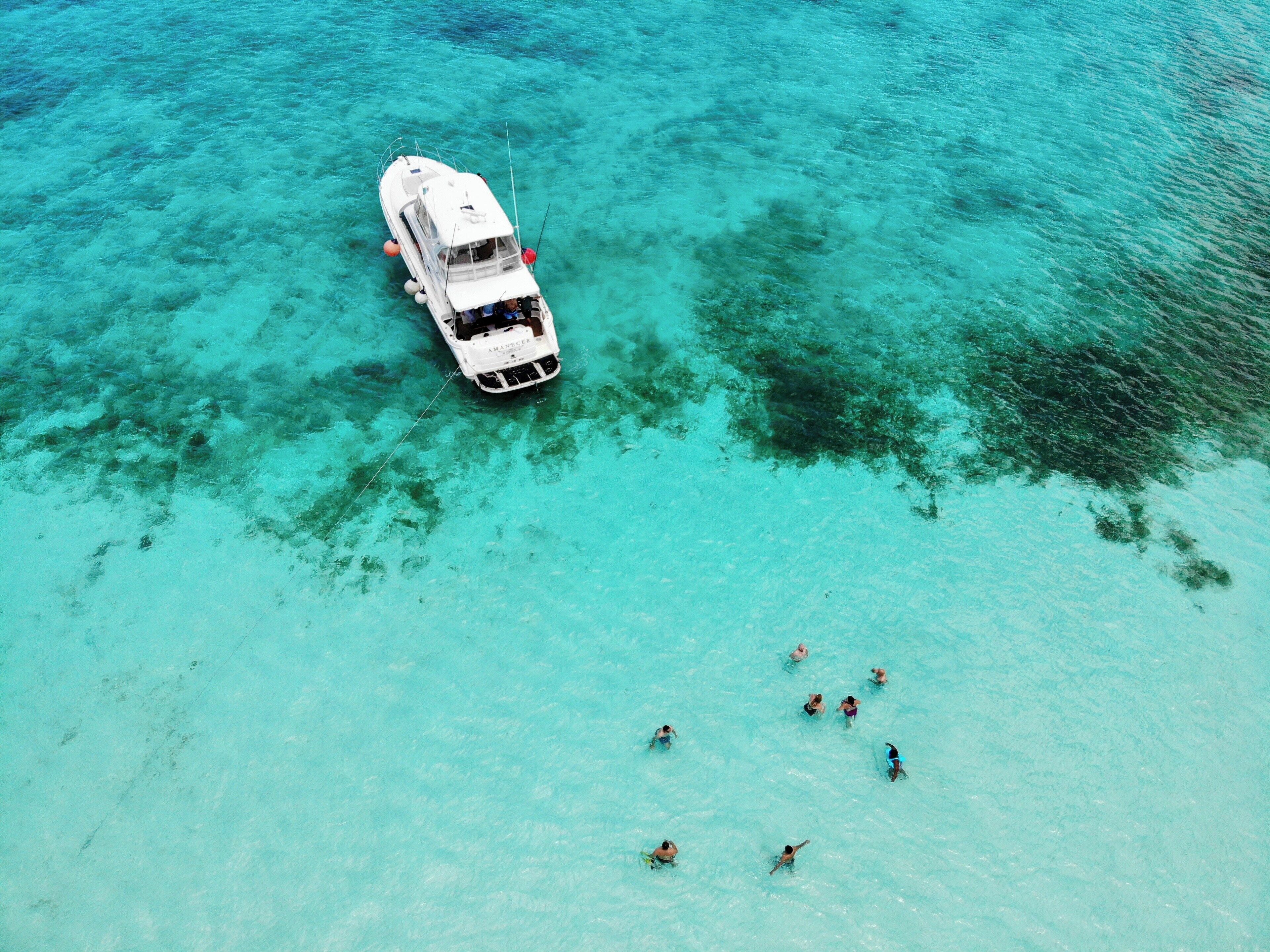 Um barco branco com cabine e um barco menor na água.