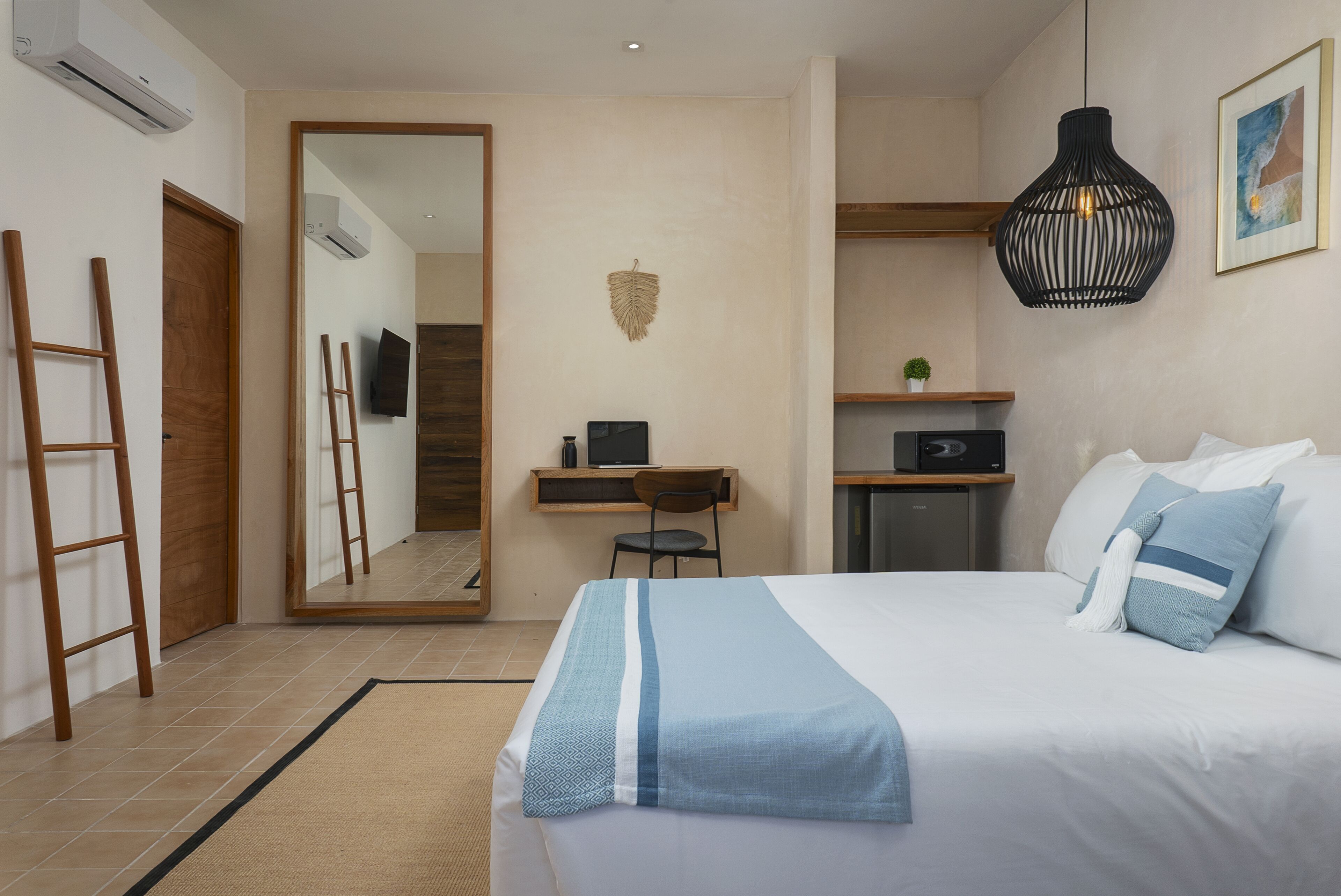 Ein Hotelzimmer mit Bett, Schreibtisch, Stuhl, Fernseher und Spiegel.