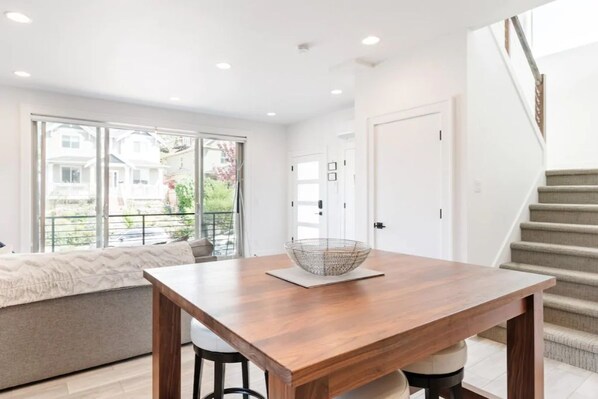 Un comedor moderno con una mesa de madera, una cesta tejida y vistas a un balcón con sofá.