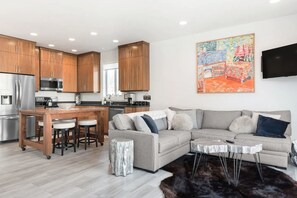 Una cocina moderna con armarios de madera, electrodomésticos de acero inoxidable y una isla central con taburetes.