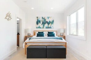 Un dormitorio moderno con una cama grande, dos mesitas de noche y un ventanal amplio.